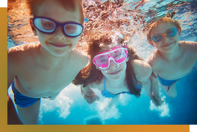 Underwater image of three smiling kids inside a pool